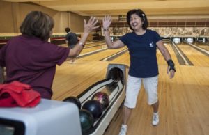 Pauline Fujino, 79, left, of Santa Ana, gives Anne Lastimado, 67, of Tustin, a high-five following her strike early one morning at the Linbrook Bowling Center in Anaheim. Both are members of the Nikkei Seniors bowling group. MARK RIGHTMIRE, THE OC REGISTER